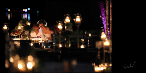 Wedding couple sitting at a venue table covered in candles and flowers